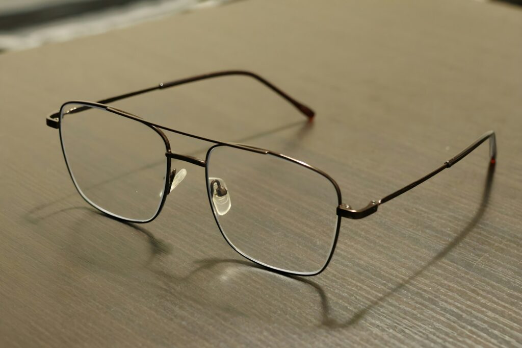 Eyeglasses sit on a light-colored, wooden surface.